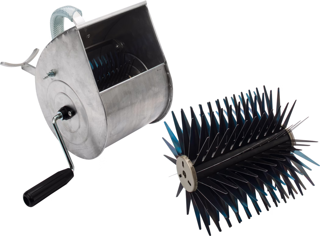 Pajarito_Dummy_Spray plasterer complete_014495_014496_2021-03 Ein handbetriebenes Metallgerät auf weißem Hintergrund, bestehend aus einem zylindrischen Aluminiumgehäuse mit seitlich montiertem Kurbelgriff und einer offenen oberen Kammer. Daneben liegt eine abnehmbare zylindrische Walze, dicht besetzt mit zahlreichen dünnen, versetzten schwarzen und blauen Zinken oder Klingen, die scharf wirkende kammartige Reihen bilden. Das Gerät wird vermutlich manuell betrieben, indem die Kurbel gedreht wird, wodurch die Innenwalze rotiert und Arbeiten wie Bürsten, Kämmen, Vertikutieren oder die Bearbeitung von Oberflächen und Entfernen von Ablagerungen ausgeführt werden; sichtbare Details sind ein geriffelter Kunststoffgriff, Metallbefestigungen und ein kurzes flexibles Schlauchstück am Gehäuse.