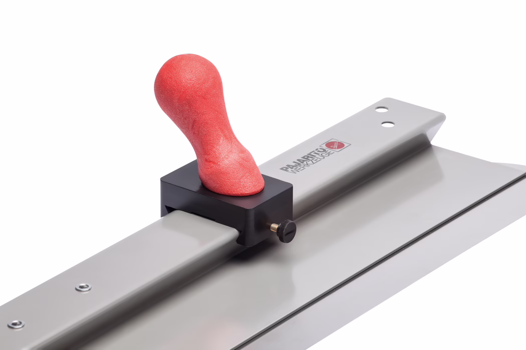 Pajarito_Dummy_Handle knob smoothing spatula_160458_2021-11 Nahaufnahme einer Metall-Glättkelle mit langer rechteckiger, flacher Klinge, die auf einer Metallschiene montiert ist; ein roter, ergonomisch geformter, weicher Griffknauf ist in einem schwarzen Kunststoffklemmblock mit einer Messing-Zugschraube eingespannt. Glatte silbergraue Metallflächen reflektieren die Studiobeleuchtung; das Werkzeug ist schräg vor weißem Hintergrund fotografiert, so dass die Struktur des roten Griffs sowie Details des Klemmblocks und der Klinge sichtbar sind.