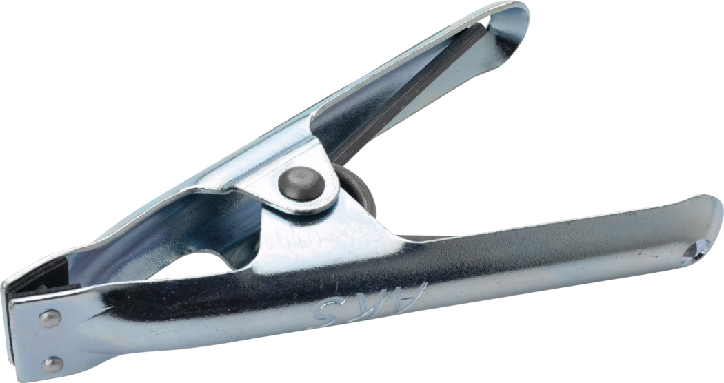 Pajarito_Dummy_Spring clamp_037090_2021-02 Nahaufnahme einer Metallzwinge: eine silberfarbene, verzinkte Stahlklammer mit zwei flachen Griffen, die durch ein genietetes Gelenk verbunden sind, und einer sichtbaren Spiralfeder, die zum Greifen, Halten oder Festklemmen von Gegenständen dient. Die Backen haben leicht abgerundete Enden und auf einem Griff sind geprägte Buchstaben erkennbar; die Oberfläche ist glänzend mit feiner Struktur und leichten Fertigungsmarken. Das Objekt ist vor weißem Hintergrund isoliert und diagonal im Bild angeordnet.