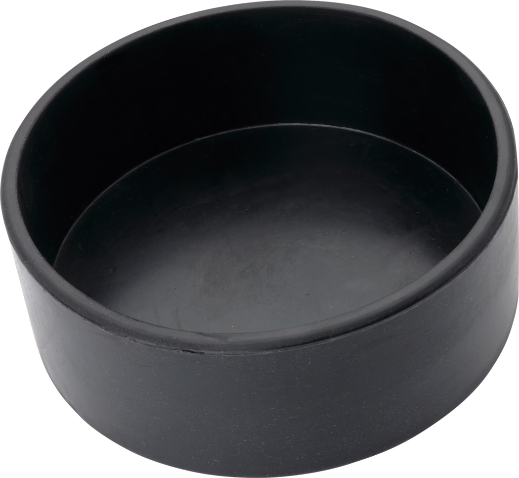 Pajarito_Dummy_Plaster cup cylindr Form rubber_038495_037186_2021-02 Eine runde schwarze Gummikappe oder Schutzstopfen mit flacher, zylindrischer, becherartiger Form, matter Oberfläche mit leichten Kratzern und Gebrauchsspuren, fotografiert aus schräger Draufsicht auf weißem Hintergrund.