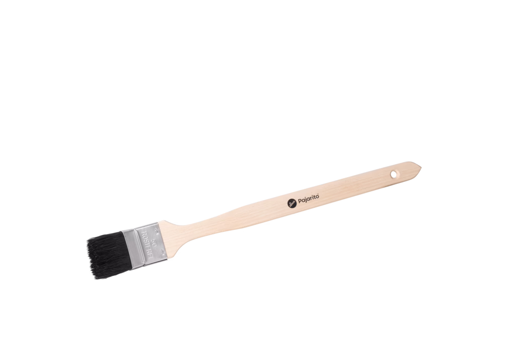 Langer Maler- bzw. Flachpinsel mit naturfarbenem, schlankem Holzgriff, fotografiert vor weißem Hintergrund. Der helle Buchenholzgriff ist ergonomisch geformt, besitzt am Ende ein kleines rundes Aufhängeloch und trägt das schwarze Markenlogo 'pajarito' auf der Stange. Eine gecrimpte silberne Metallzwinge hält dichte, kurze schwarze Borsten; die Zwinge ist mit '50' und 'ROSTFREI' geprägt, was auf eine 50-mm-Breite und rostfreien Stahl hinweist. Der Pinsel liegt diagonal im Bild, zeigt Holzmaserung, saubere Borstenenden und die Metallfassung; er wirkt neu und unbenutzt und eignet sich für Kanten-, Leisten- und Detailarbeiten.