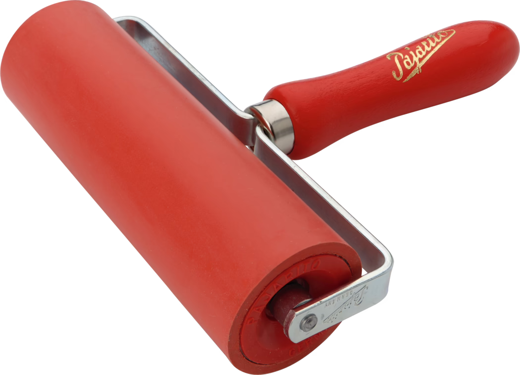 Nahaufnahme einer roten Gummirakelwalze, die beim Druck und zum Glätten von Oberflächen verwendet wird. Die zylindrische rote Gummiwalze ist in einem U-förmigen Metallgestell montiert und besitzt einen gedrehten, rot lackierten Holzgriff mit goldener Beschriftung; Oberfläche der Walze und Metallglanz sind vor weißem Hintergrund gut sichtbar.