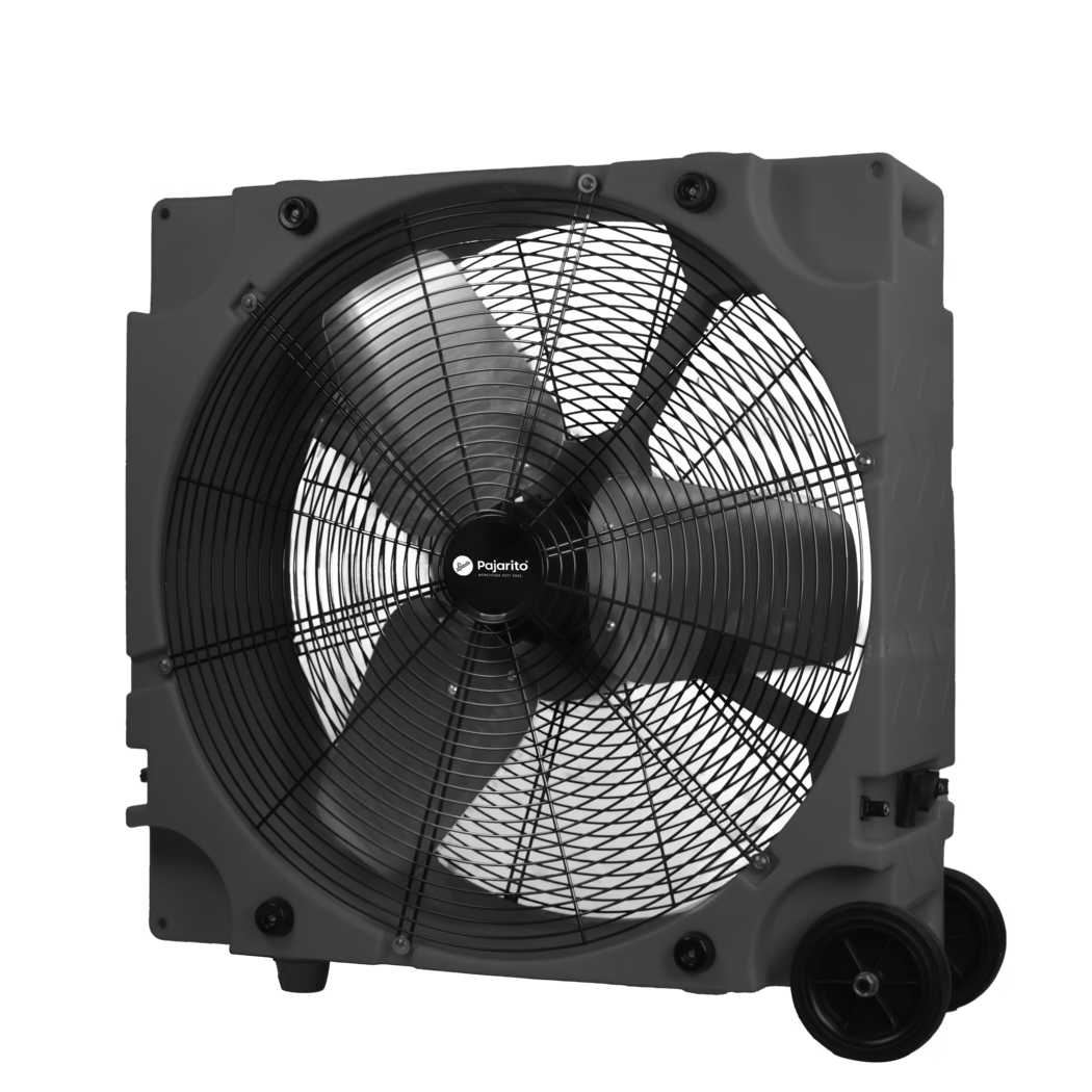 Pajarito_Dummy_Ventilator_181154_2024-08 Detailaufnahme eines großen, tragbaren Industrie-Axialventilators in einem rechteckigen Kunststoffgehäuse. Das Bild zeigt die Vorderseite des Ventilators mit einem schwarzen Metall-Schutzgitter, drei breiten gebogenen Lüfterblättern und einer zentralen Nabe mit der Aufschrift "Pajarito". Das geformte Kunststoffgehäuse verfügt über integrierte Griffe, sichtbare Befestigungspunkte, Gummifüße und zwei Transportrollen unten rechts. Schrauben und Gummipuffer sichern das Schutzgitter am Gehäuse. Kontrastreiche monochrome Aufnahme, die die Oberflächenstrukturen und Details der Metallblätter, des Gitters und des Kunststoffgehäuses betont.