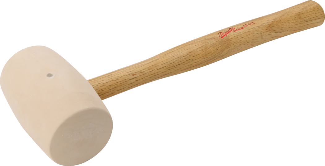PAJARITO_Dummy_Rubber mallet _089408_2021-02 Nahaufnahme eines Gummihammers mit hellem beige-farbenem, zylindrischem Kopf und glattem Holzgriff. Der konisch geformte Eichenholzgriff zeigt sichtbare Holzmaserung und eine kleine rote Markenaufdruckung in der Nähe des oberen Endes. Der Hammer ist vor weißem Hintergrund abgebildet, wodurch die einfache Werkstatt-Optik und die leicht matte Oberfläche des Kopfes betont werden.